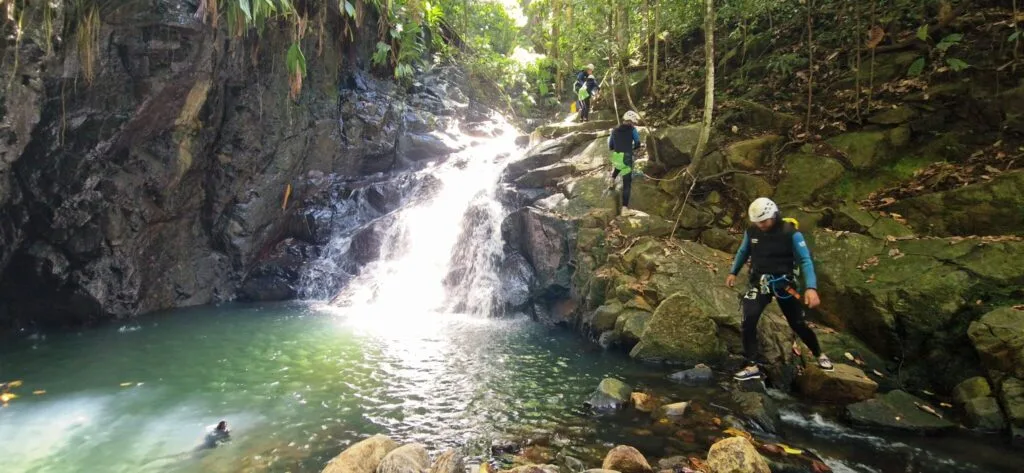 Canyonistes au pied d'une cascade, au bord d'une vasque, canyoning à Deshaies