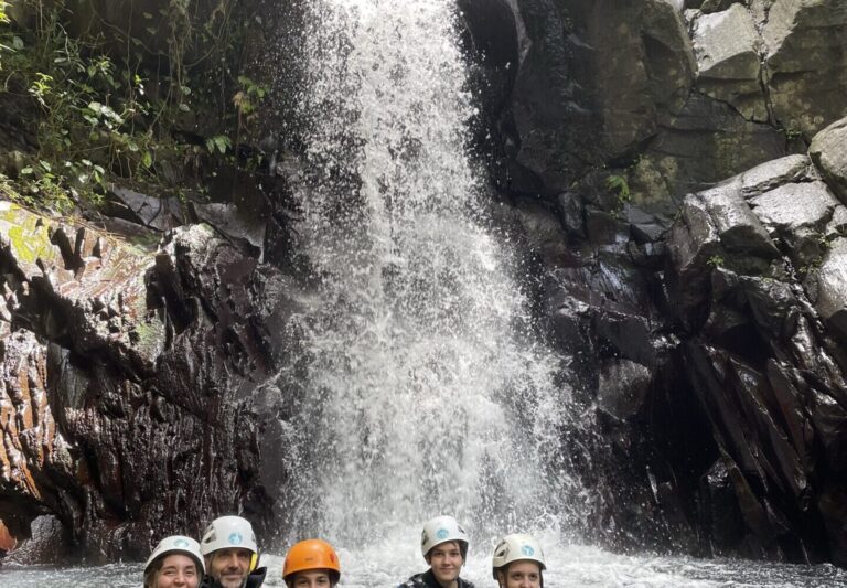 Groupe de canyonistes dans la vasque au pied d'une grande cascade, Guadeloupe