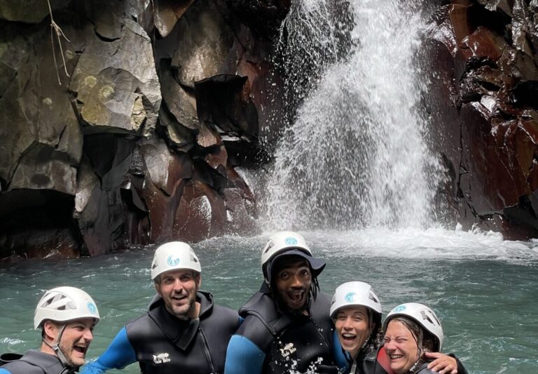 Groupe souriant dans la vasque au pied d'une cascade, canyoning en Guadeloupe