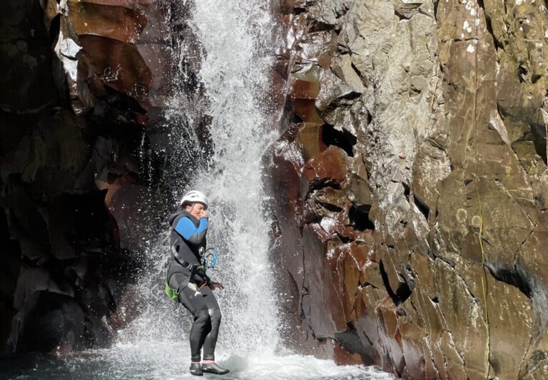 Canyoniste en rappel sous une cascade étroite entre des parois rocheuses, Guadeloupe
