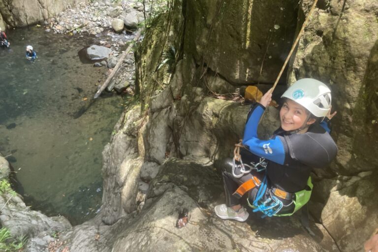 Canyoniste souriante en rappel au-dessus d'une vasque, canyoning en Guadeloupe